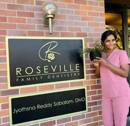 Dr. Reddy beside the Roseville Family Dentistry sign